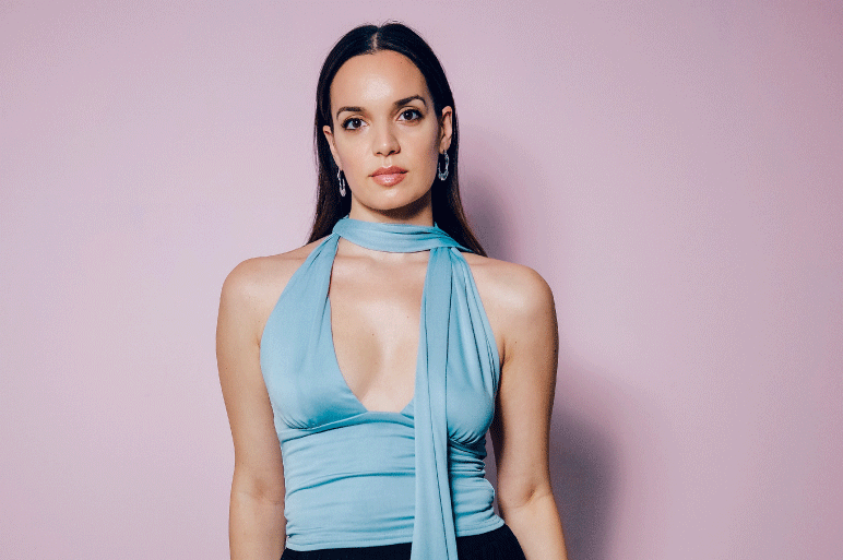 Tamara Jokić poses in a blue top against a light pink background